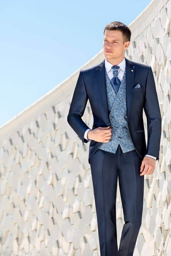 El Renacer del Traje Clásico - Hombre elegante en traje azul posando frente a fondo arquitectónico moderno.